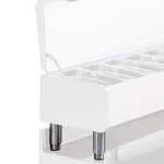 White rectangular display/storage unit with a transparent hinged lid and metal legs, showing multiple interior compartments.